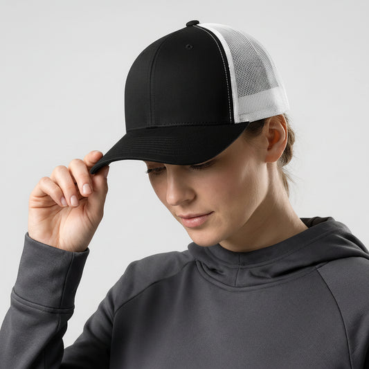 Person wearing a black and white cap with a reflective logo on a light gray background