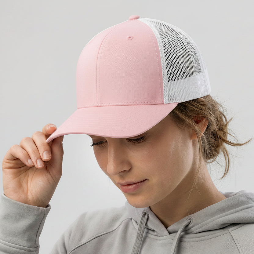 Person wearing a pink cap with a white mesh back on a gray background