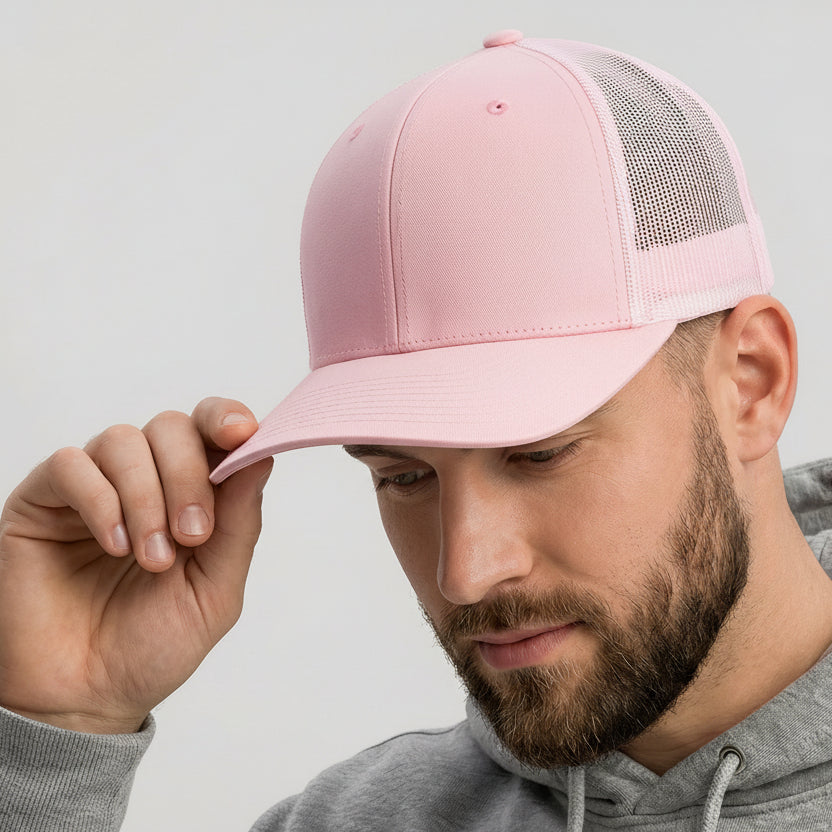 Man wearing a pink cap with a logo and a gray hoodie on a light gray background