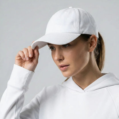 Woman wearing a white cap and hoodie against a gray background
