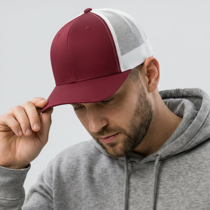 Man wearing a maroon and white cap with a gray hoodie against a light gray background