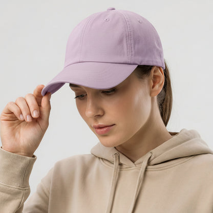 Woman wearing a beige hoodie and a purple cap on a light gray background