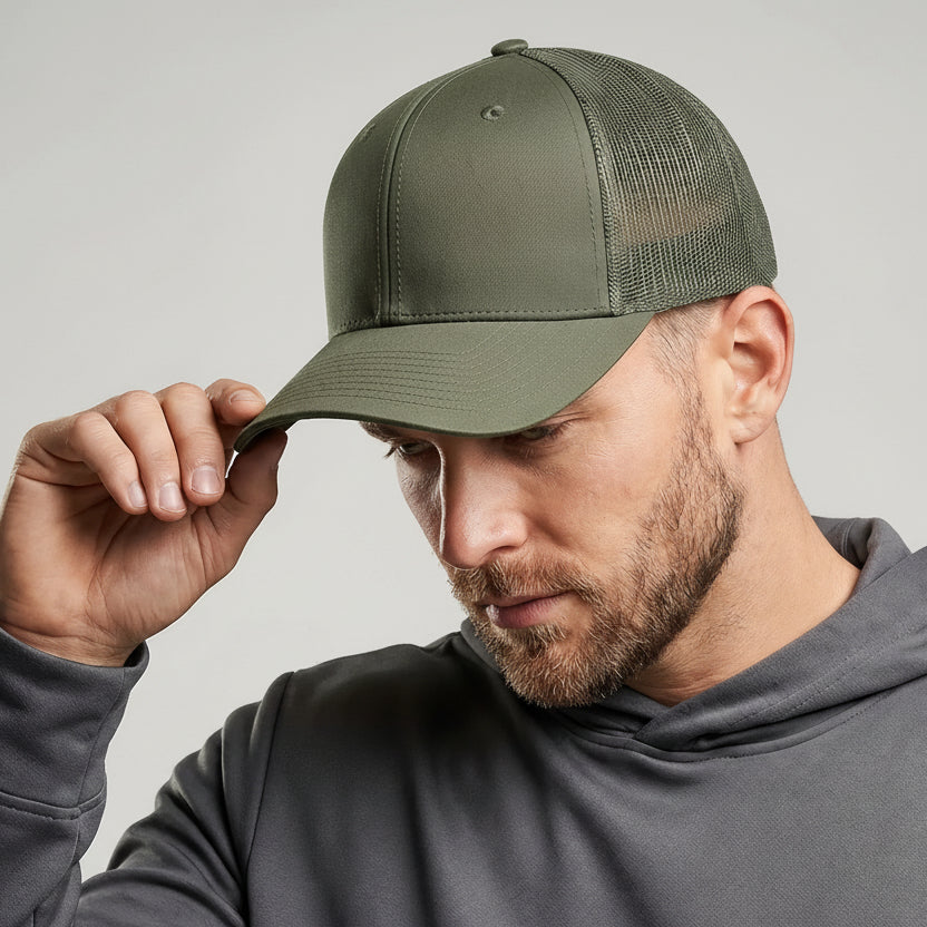 Man wearing a green cap and gray hoodie against a plain background