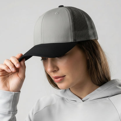 Woman holding a gray and black cap against a plain background