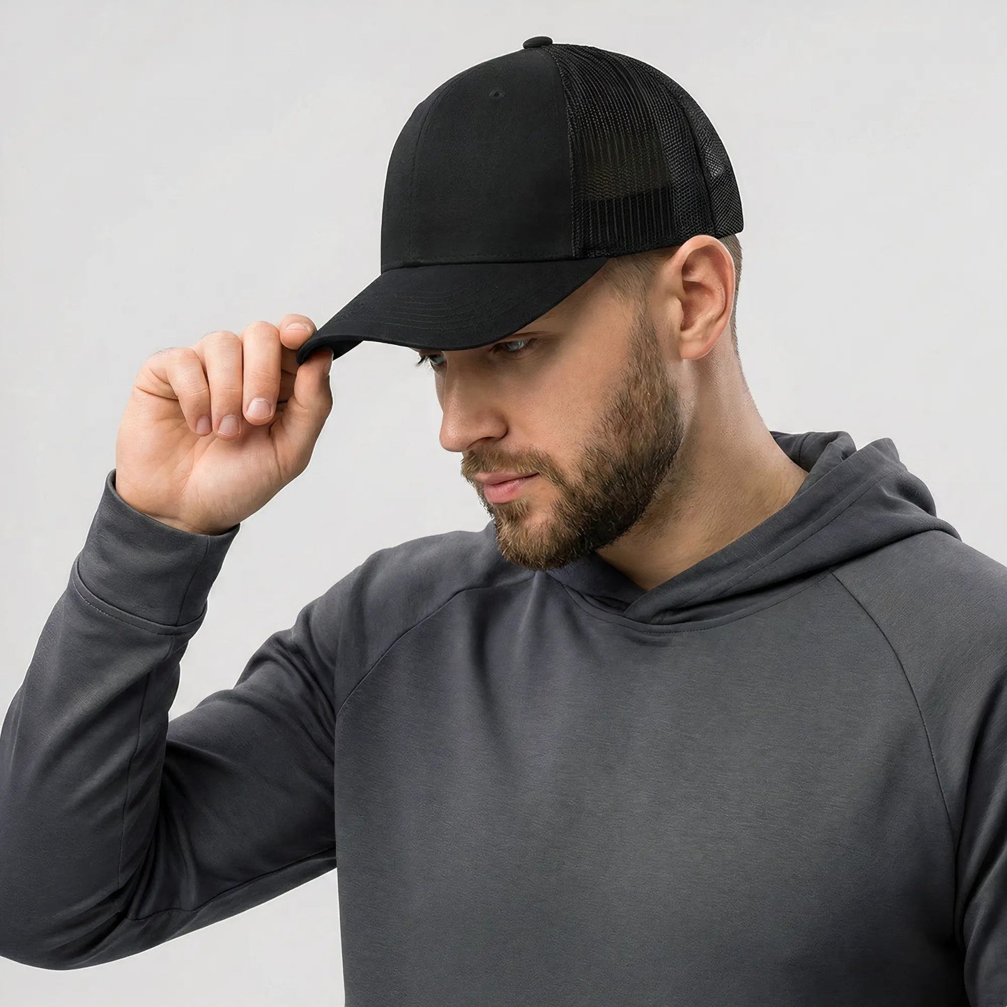 Man wearing a black cap and gray hoodie against a light gray background