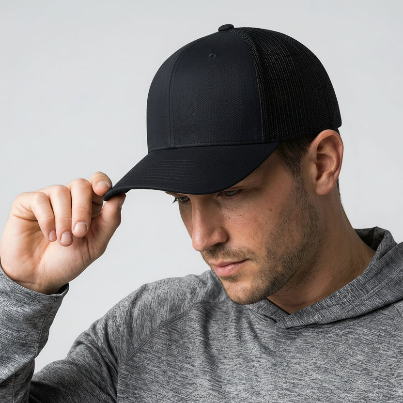 Man wearing a black cap and gray hoodie against a light gray background