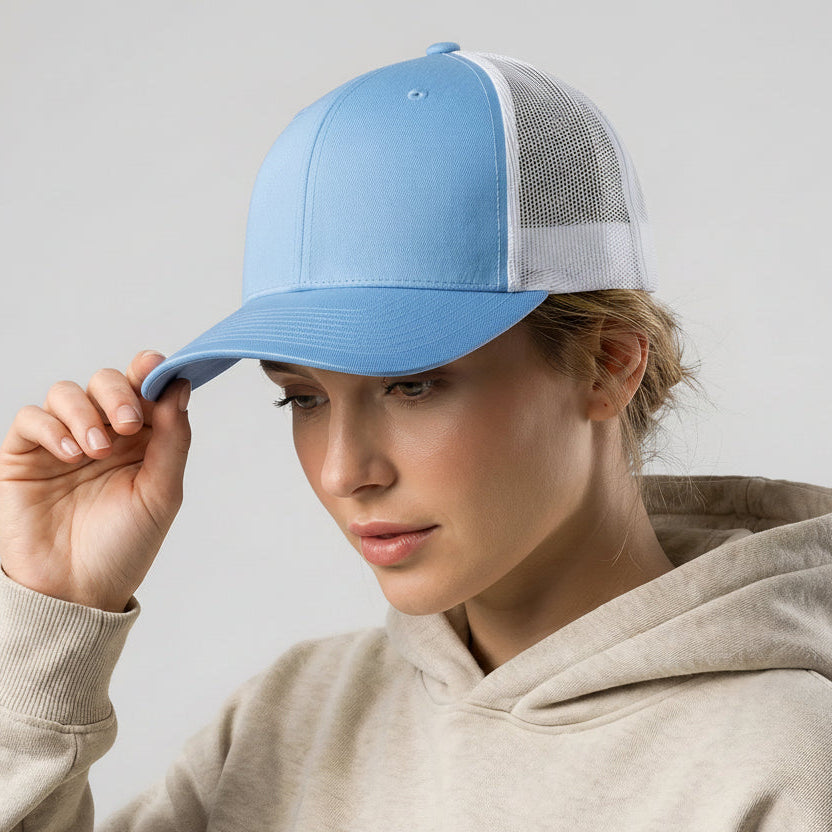 Person wearing a light blue and white cap with a beige hoodie on a plain background