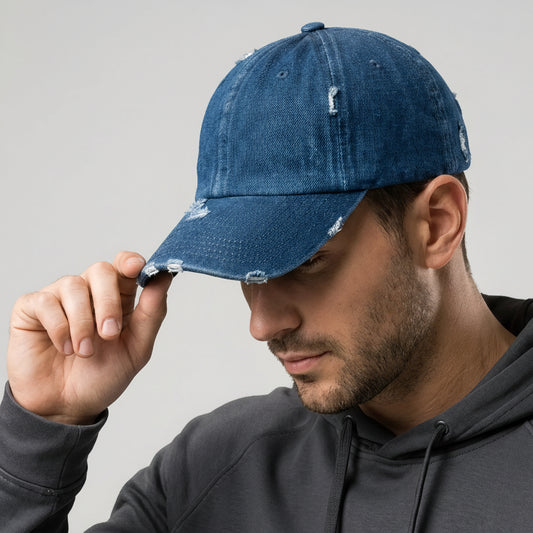 Man wearing a blue distressed cap with a gold logo on a gray background
