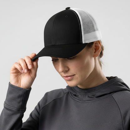 Person wearing a black and white cap with a reflective logo on a light gray background