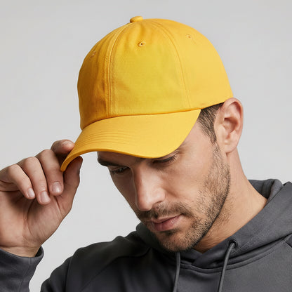 Man wearing a yellow cap with a logo and a gray hoodie on a light gray background