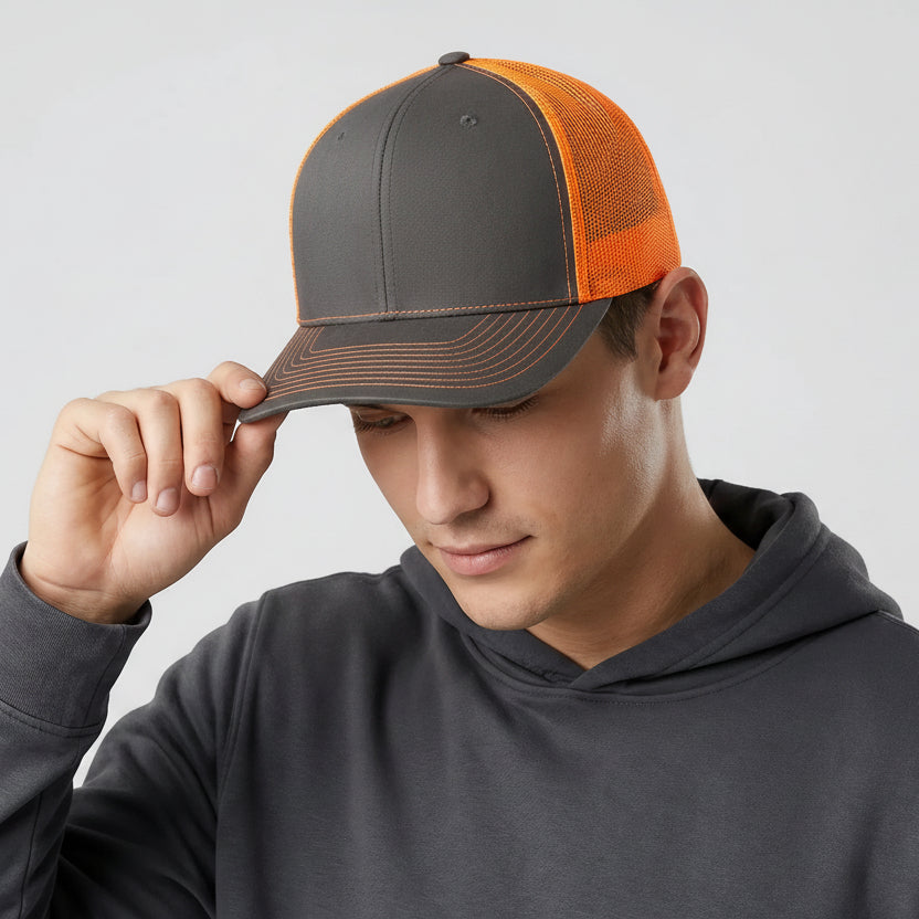 Man wearing a gray and orange cap with a gray hoodie on a light gray background