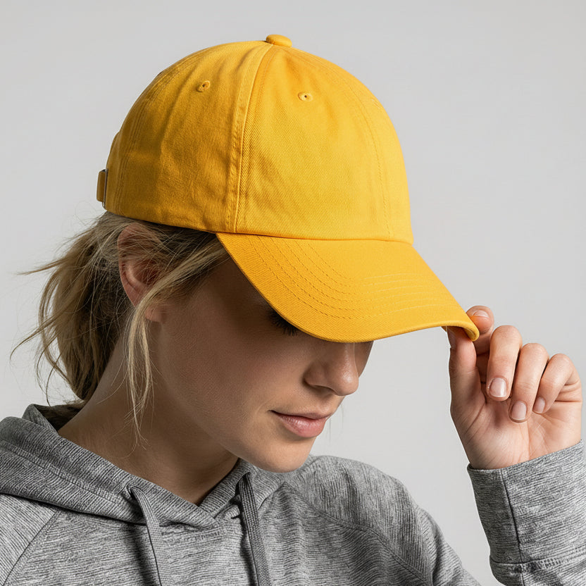 Person wearing a yellow cap with a logo, looking down, on a plain background