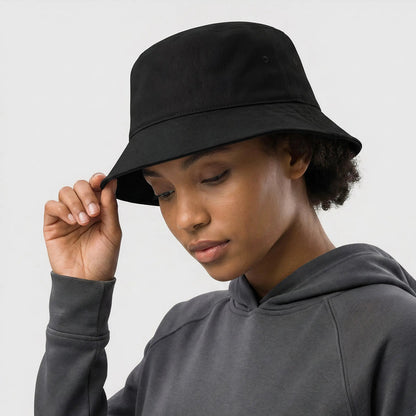 Person wearing a black bucket hat and gray hoodie against a white background