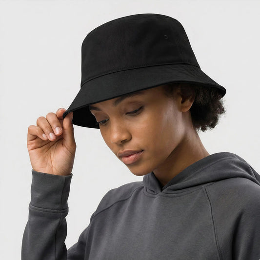 Person wearing a black bucket hat and gray hoodie against a white background