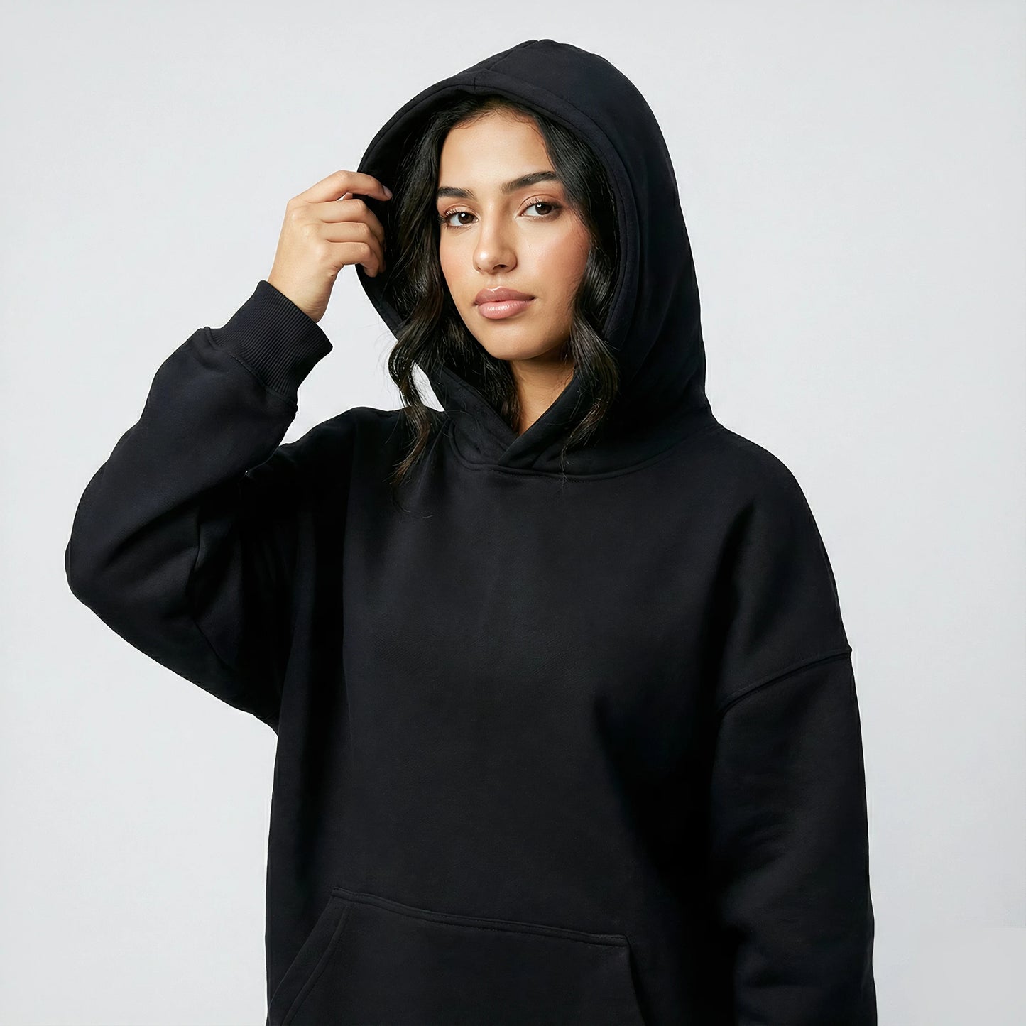 Woman wearing a black hoodie against a plain background