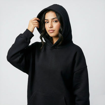 Woman wearing a black hoodie against a plain background