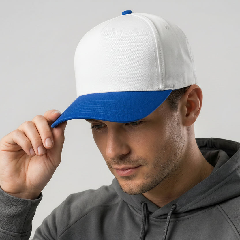Man wearing a white and blue cap with a gray hoodie on a light gray background