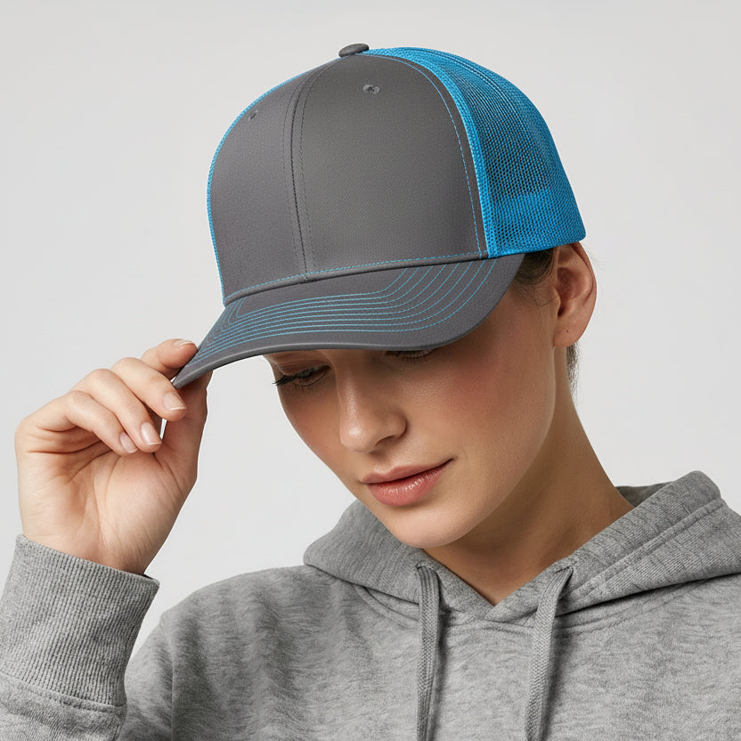 Person wearing a gray cap with blue visor and a gray hoodie on a light gray background