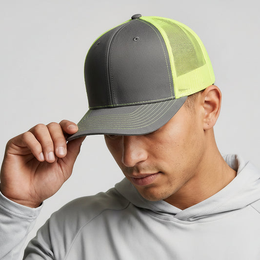 Person wearing a gray and neon yellow cap with a brand logo on a light gray background