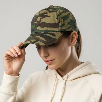 Person wearing a camouflage cap and beige hoodie against a gray background