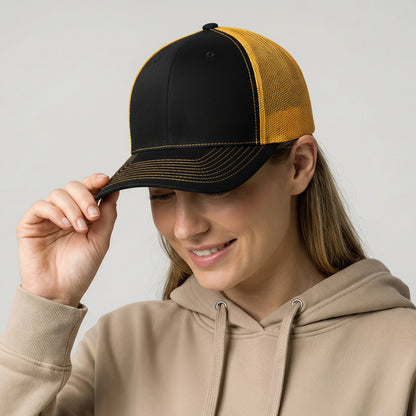 Person wearing a black and yellow cap with a rainbow sticker, holding it up to their face.