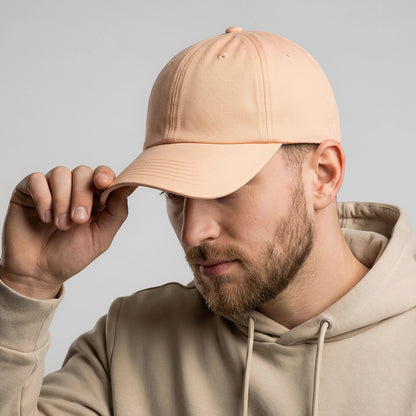 Man wearing a beige cap and hoodie with a gray background