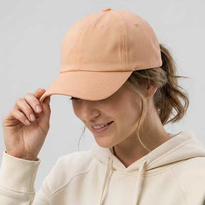 Person wearing a peach cap with a logo on a light gray background