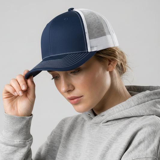 Person wearing a navy blue cap with a white mesh back and a gray hoodie on a light gray background