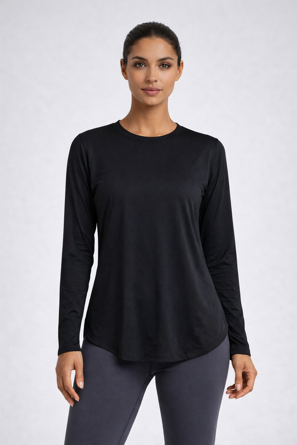 Woman wearing a black long-sleeve top and gray leggings on a white background