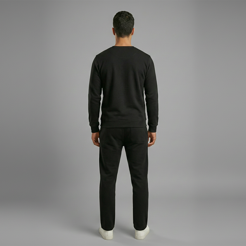 Man wearing a black sweatshirt and pants on a gray background