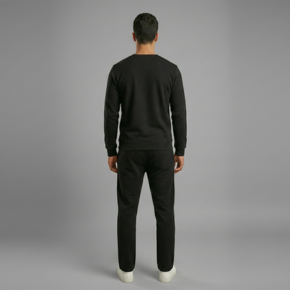 Man wearing a black sweatshirt and pants on a gray background