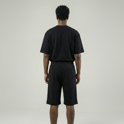 Person wearing a black t-shirt and shorts set on a plain background
