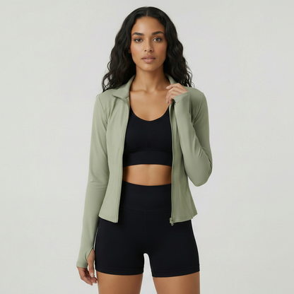 Woman wearing a green jacket over a black sports bra and shorts on a white background
