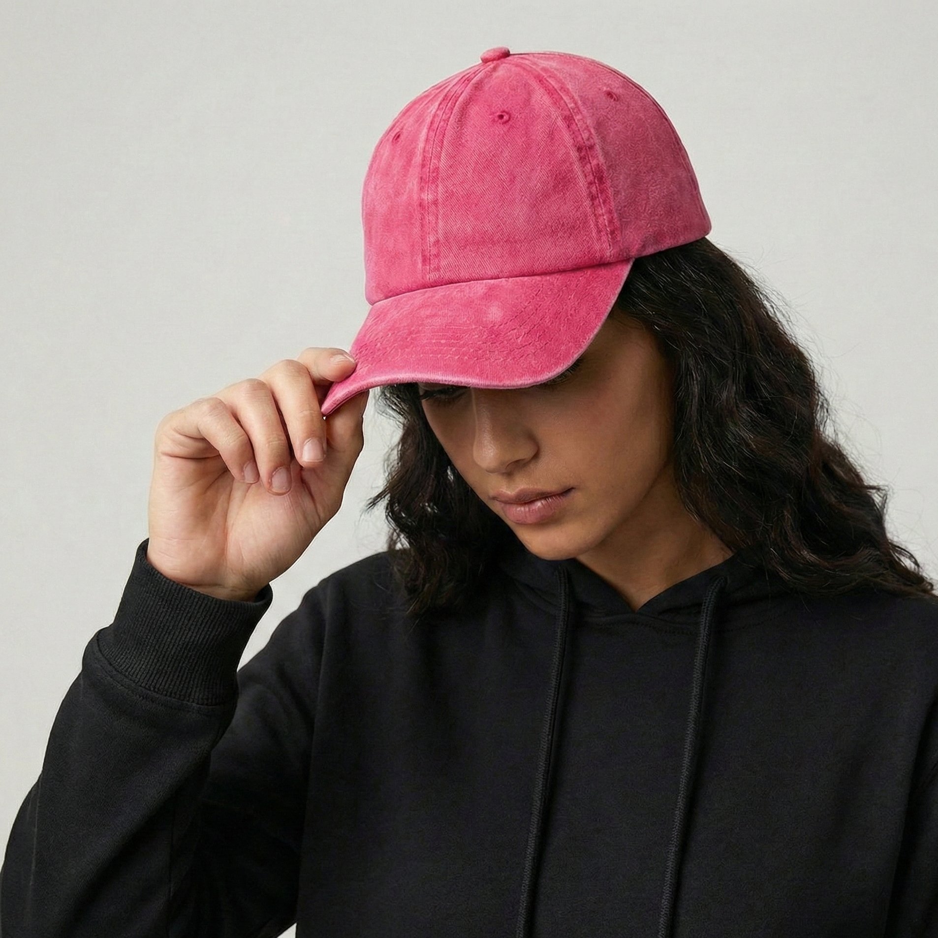 Person wearing a pink cap and black hoodie against a plain background