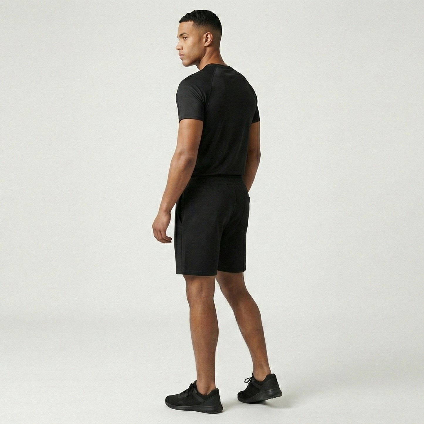 Man wearing a black t-shirt and shorts on a white background
