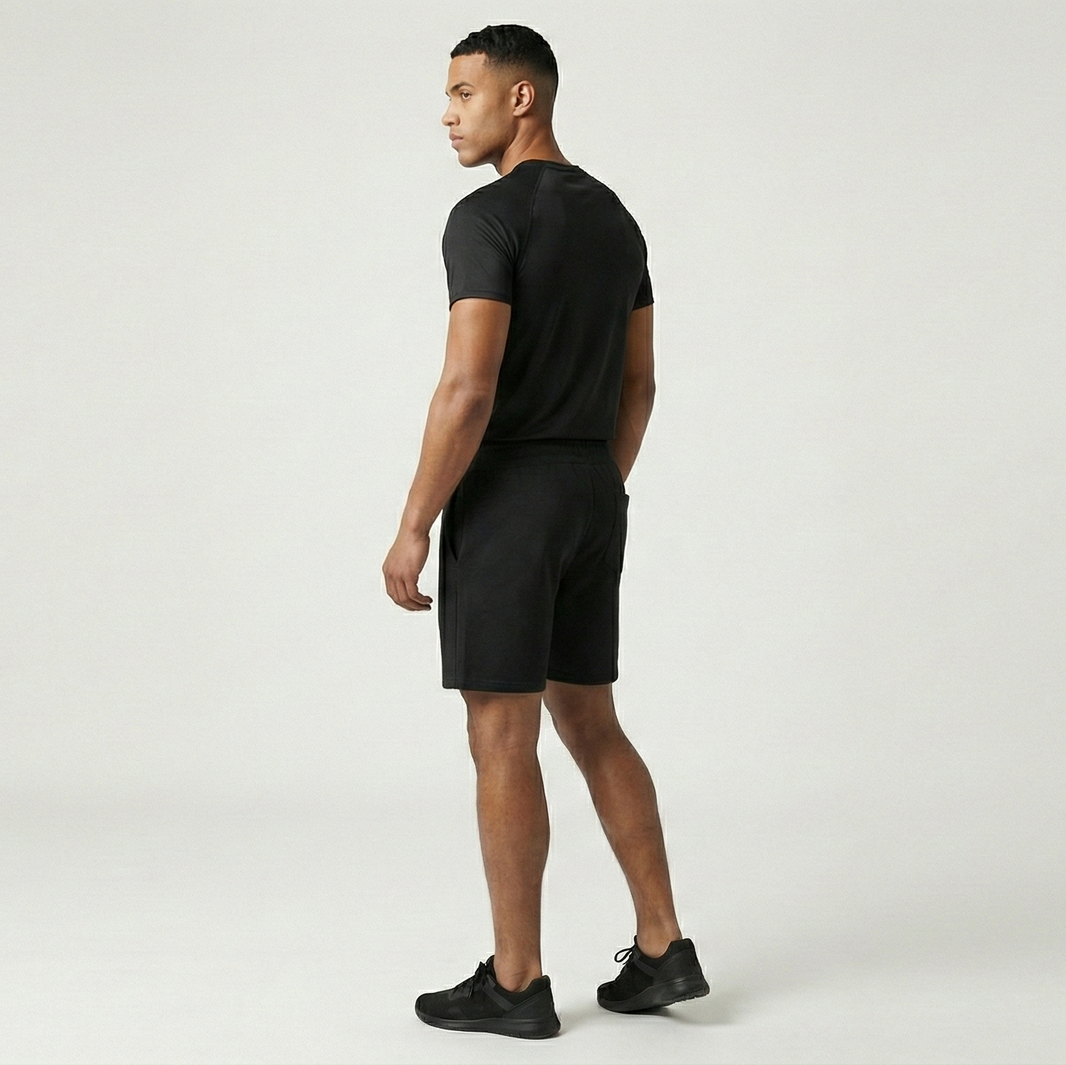 Man wearing a black t-shirt and shorts on a white background
