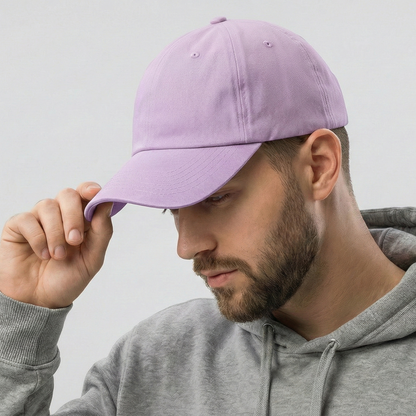 Man wearing a gray hoodie and holding a purple cap against a light gray background