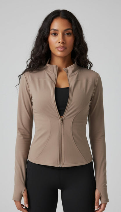 Woman wearing a beige zip-up jacket over a black top and leggings on a gray background