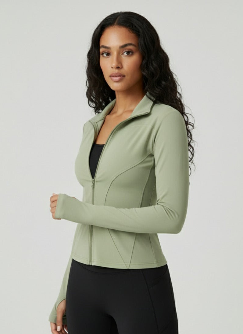 Woman wearing a light green athletic jacket and black leggings on a white background